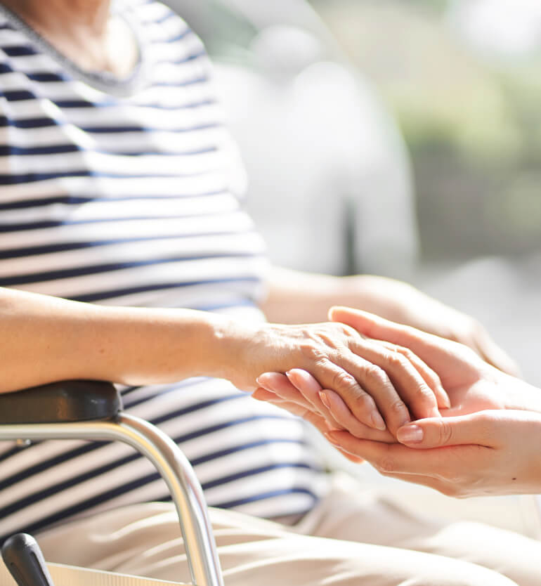 holding senior woman in wheelchairs hand