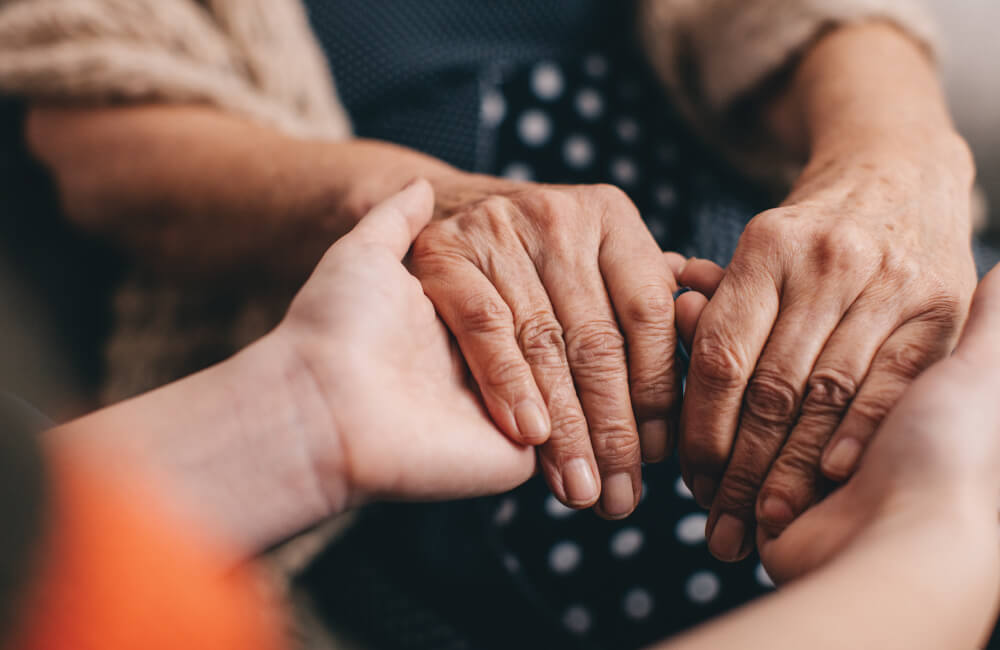 Young person holding older persons hands