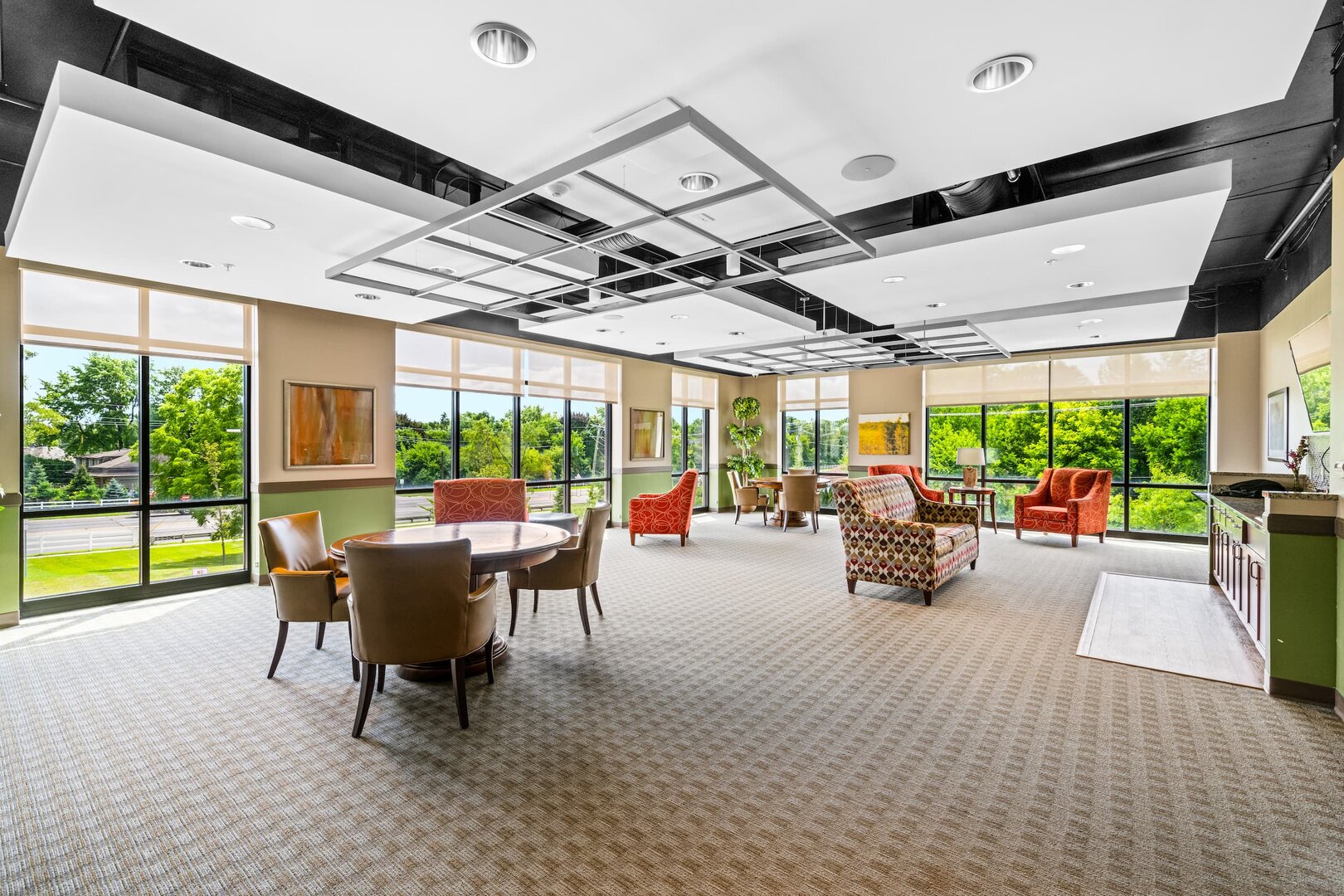 bright-community-lounge-avalon-bloomfield Spacious community area with large windows and colorful seating in a residential building.