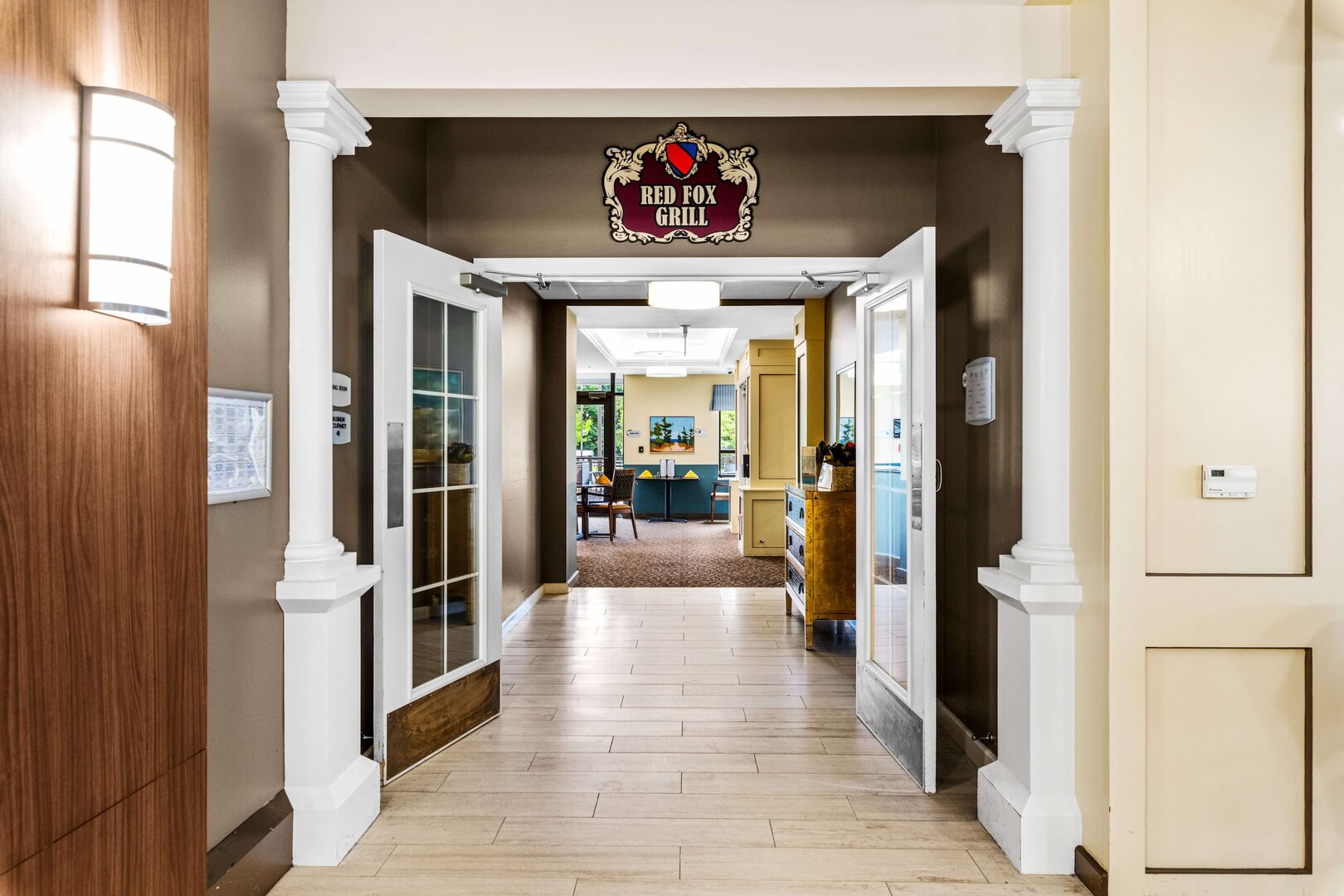 red-fox-grill-entrance-senior-community Entrance to Red Fox Grill with open double doors and dining area in senior community.