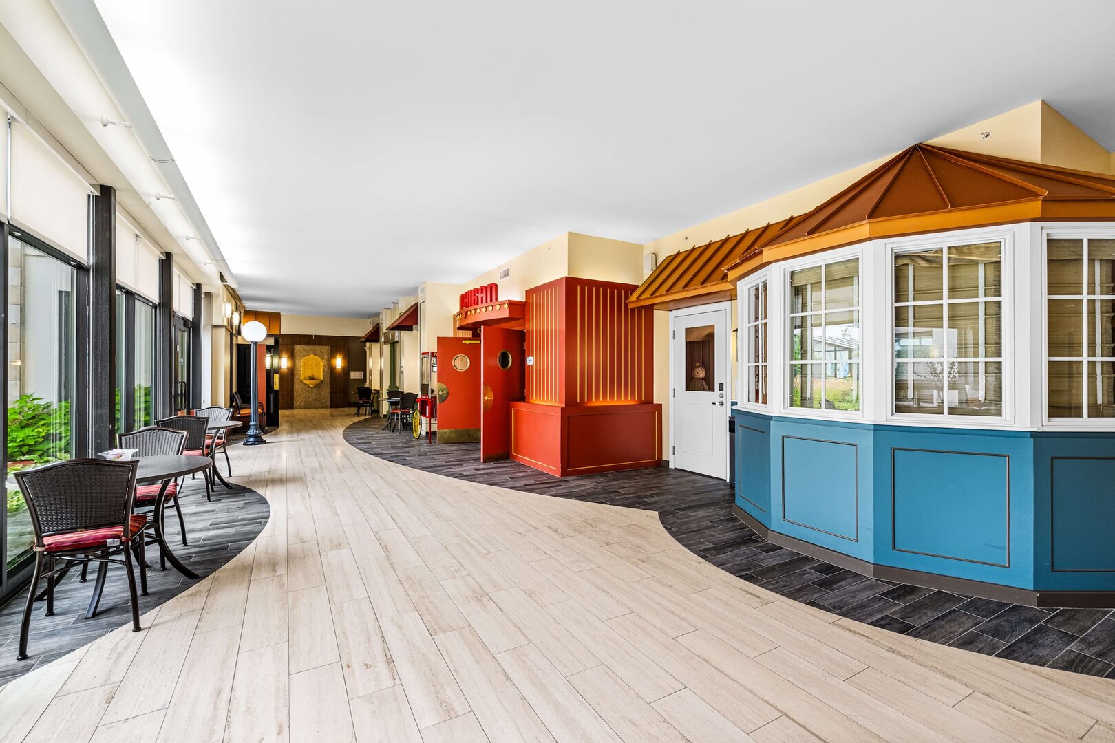 vibrant-community-interior-design Colorful interior space with storefront-style facades and seating area.