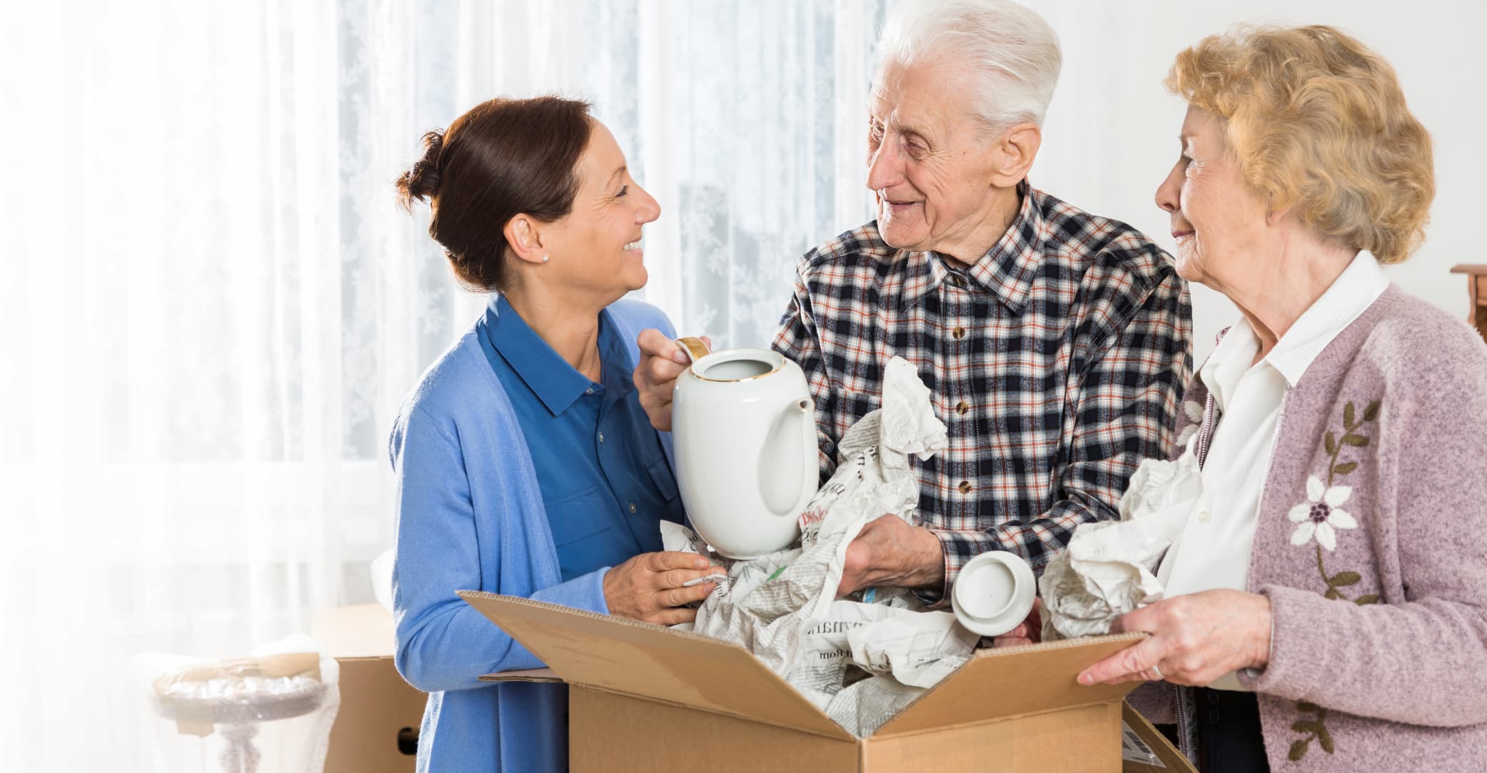 Adult woman helping senior parents downsize and pack up belongings